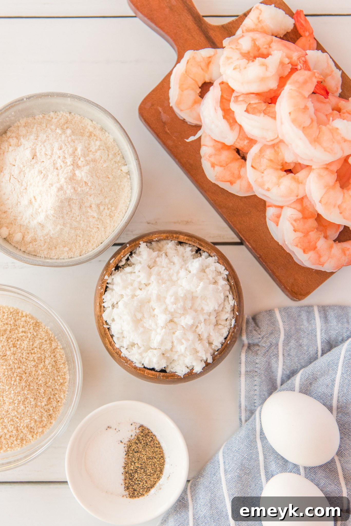 All ingredients for Air Fryer Coconut Shrimp laid out neatly on a wooden surface.