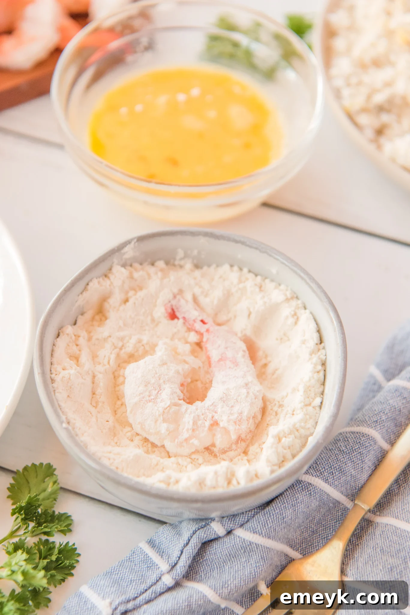 Shrimp being dredged in flour for air fryer coconut shrimp.