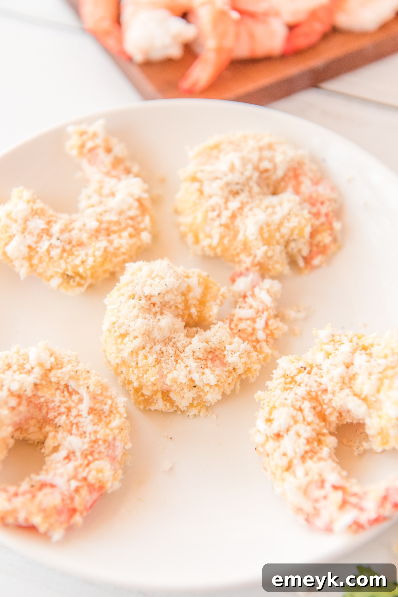Fully breaded shrimp coated in coconut flakes and breadcrumbs, ready for air frying.
