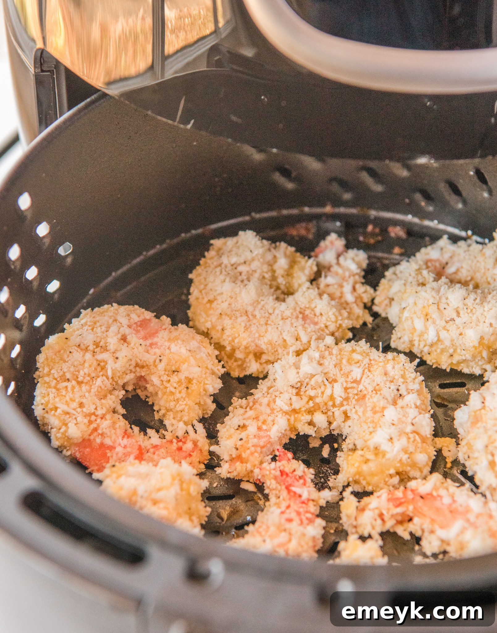 Air Fryer Coconut Shrimp cooking inside an air fryer basket, turning golden brown.