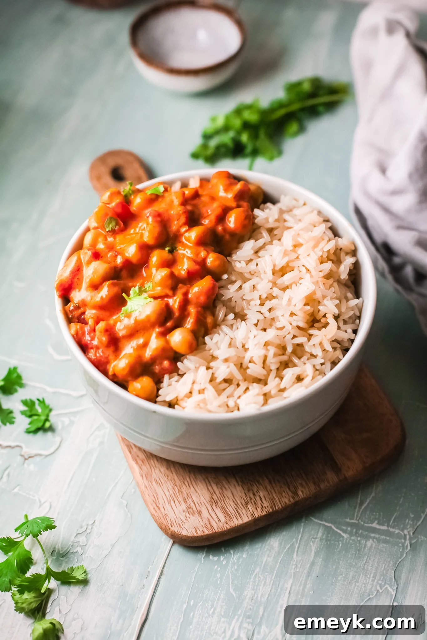 A vibrant bowl of creamy chickpea curry with rice, garnished with fresh cilantro.