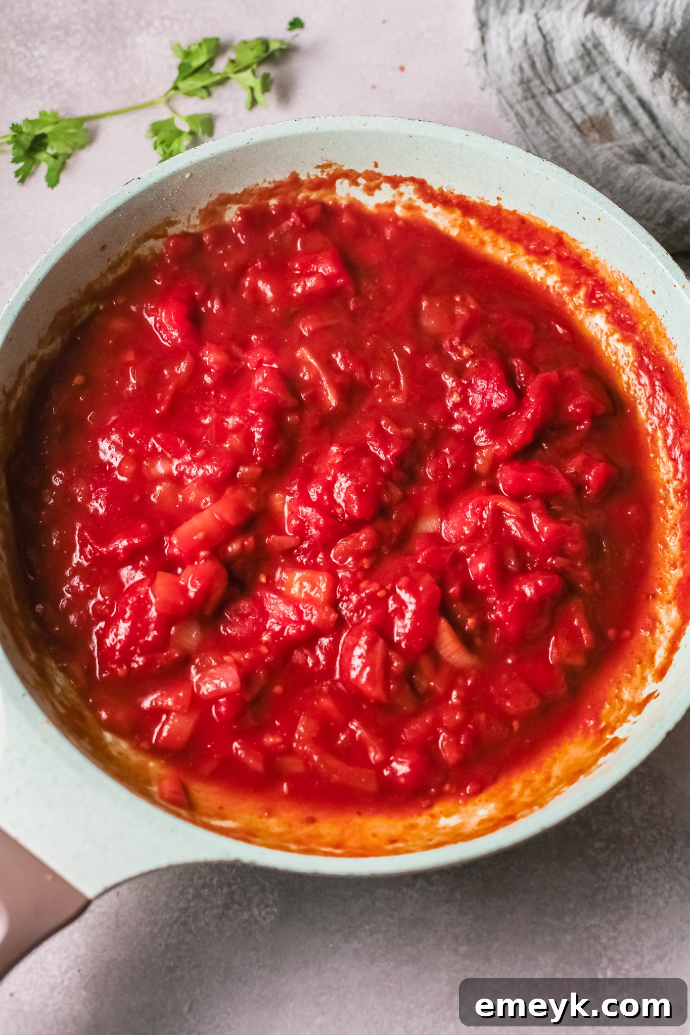 Chickpeas added to the simmering tomato and curry sauce in a skillet.