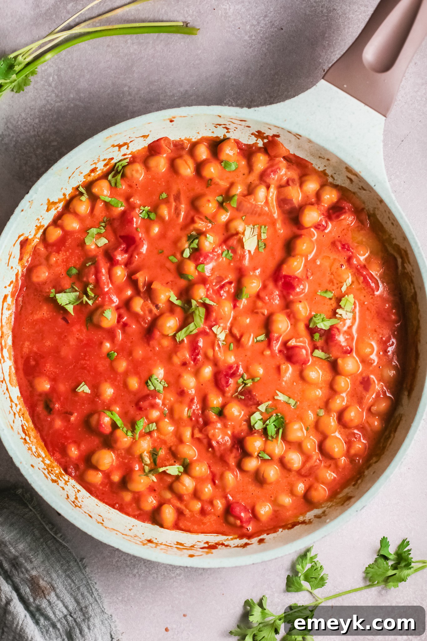 The finished chickpea curry in a skillet, garnished with fresh herbs, ready to be served.