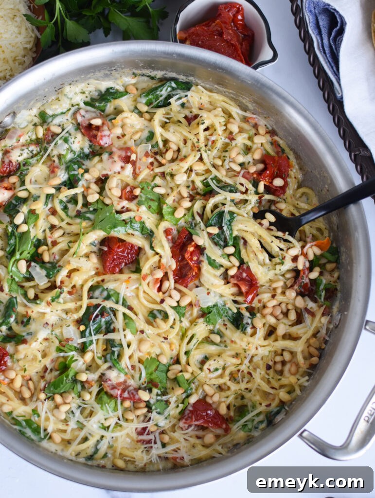 Creamy Sun-Dried Tomato Pasta Recipe with a spoon in the pan, highlighting the rich sauce and vibrant ingredients.
