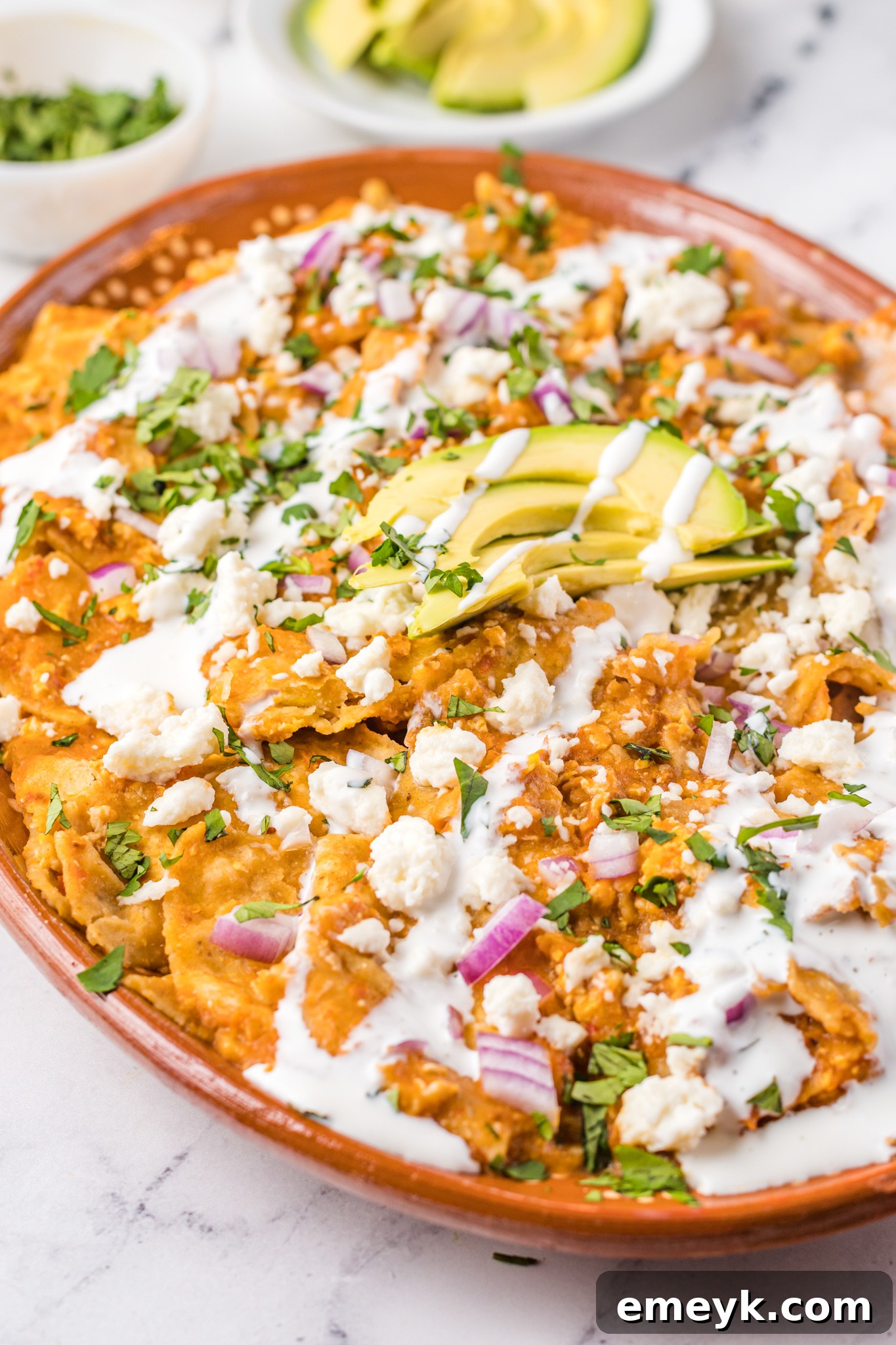 Chilaquiles Rojos Recipe on a platter with avocado on top.