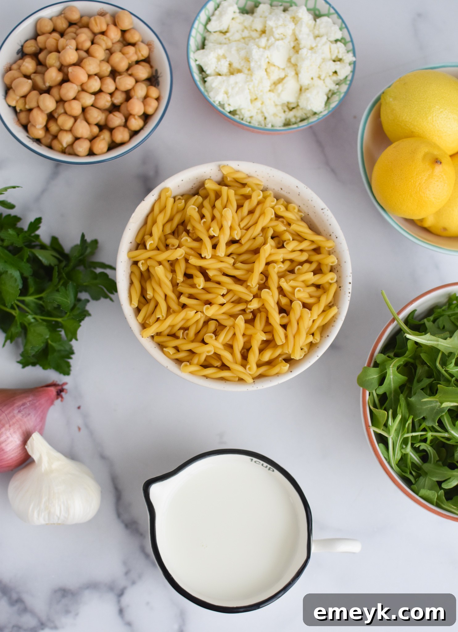Ingredients for Chickpea Pasta Recipe with Feta laid out on a table including pasta, lemons, feta cheese, and spices.