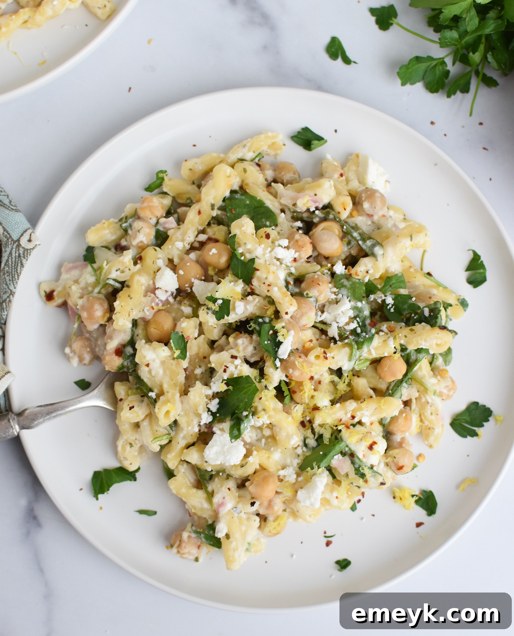 A white plate of Chickpea Pasta with Feta garnished with fresh parsley.