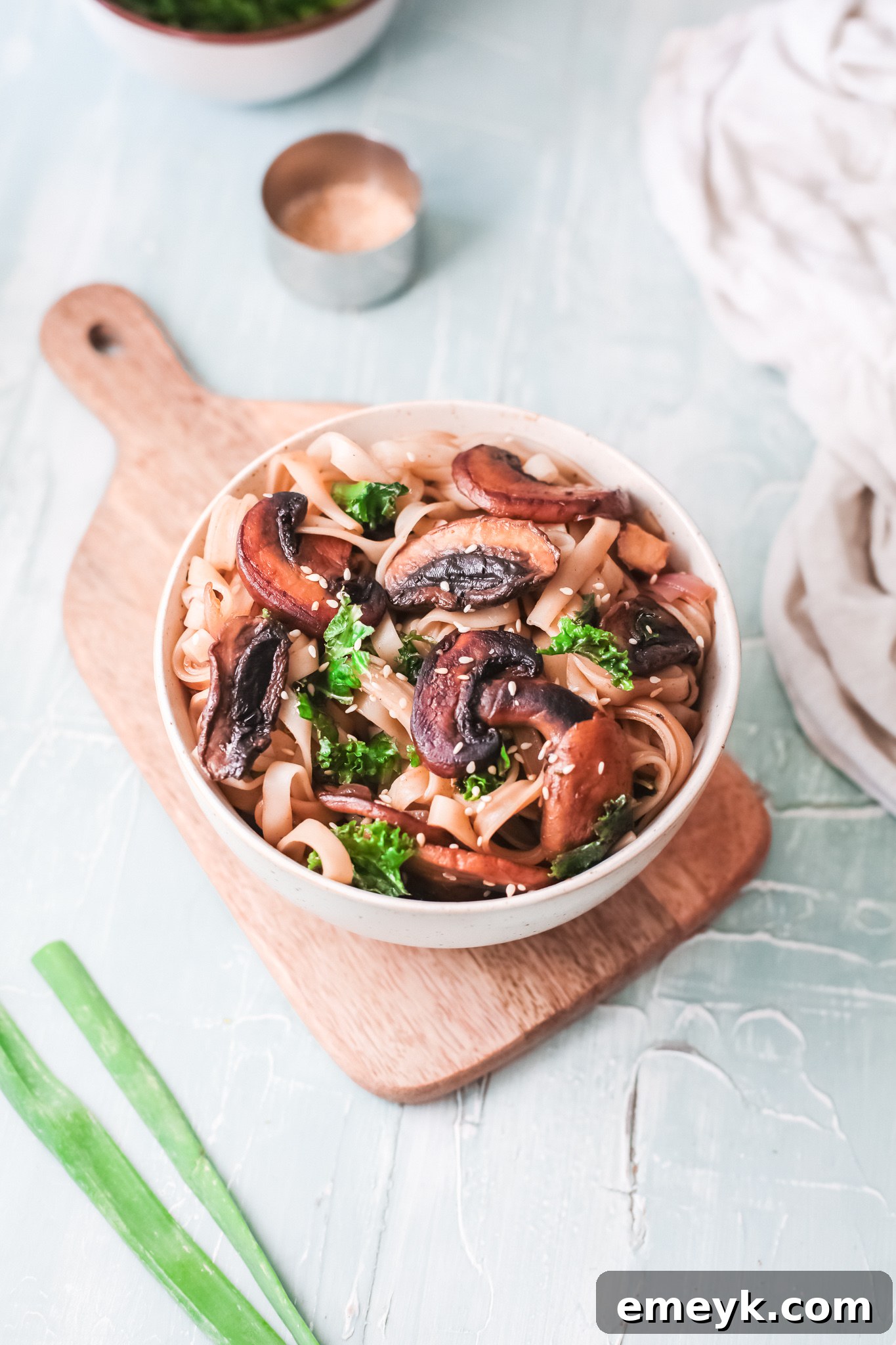 Easy Korean Noodles Recipe served in a white bowl, garnished with sesame seeds and green onions.