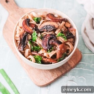 Easy Korean Noodles Recipe served in a white bowl with green onions and sesame seeds.