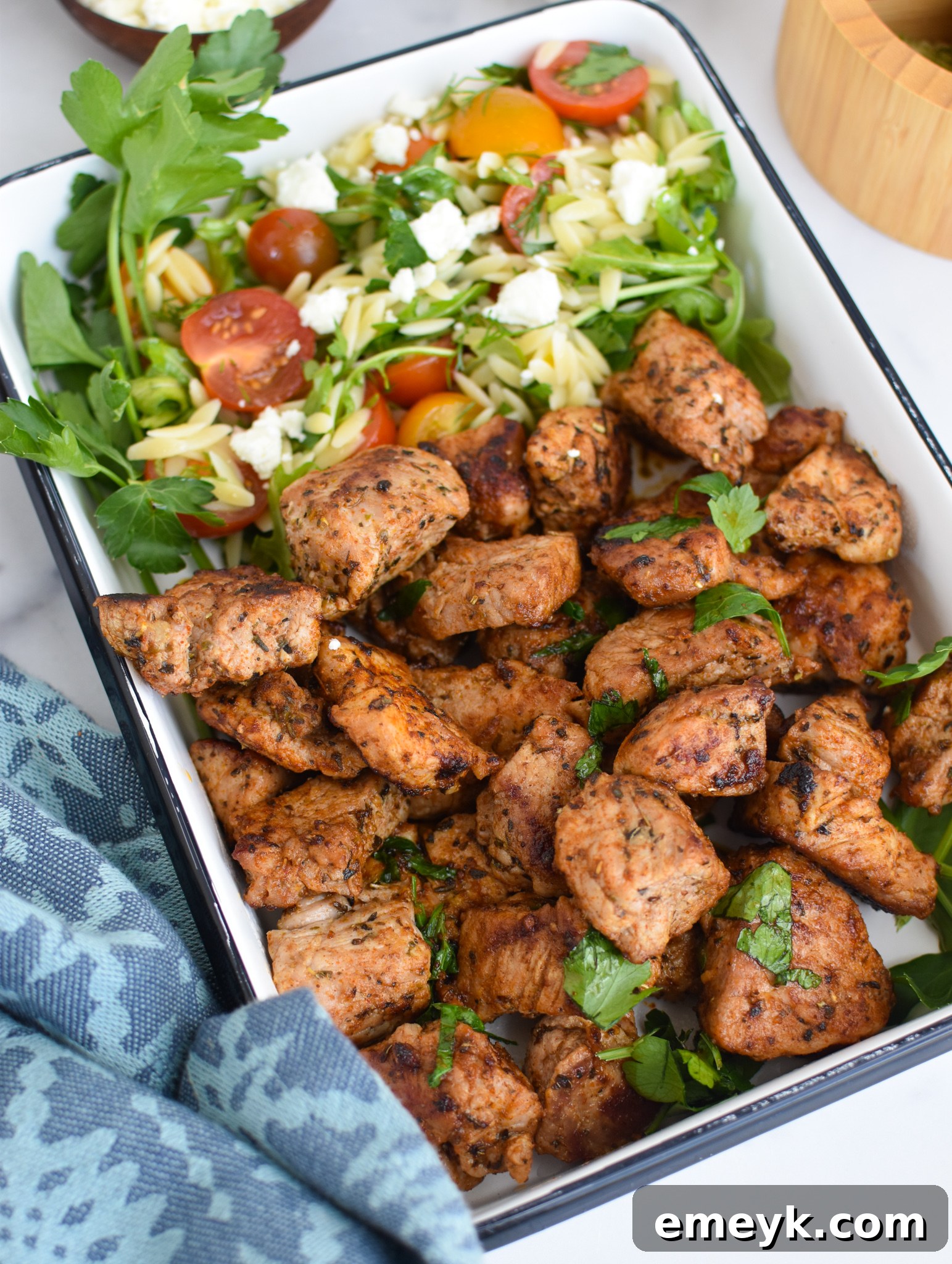 Delicious Cast Iron Pork Tenderloin served in a white square dish with herbs.