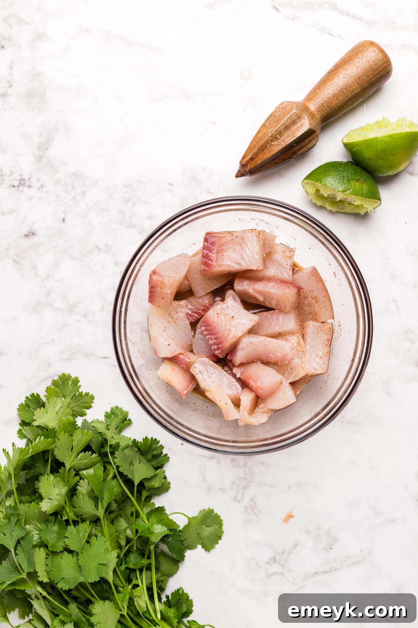 Crispy Air Fryer Tilapia 5 Tilapia pieces marinating in a bowl.