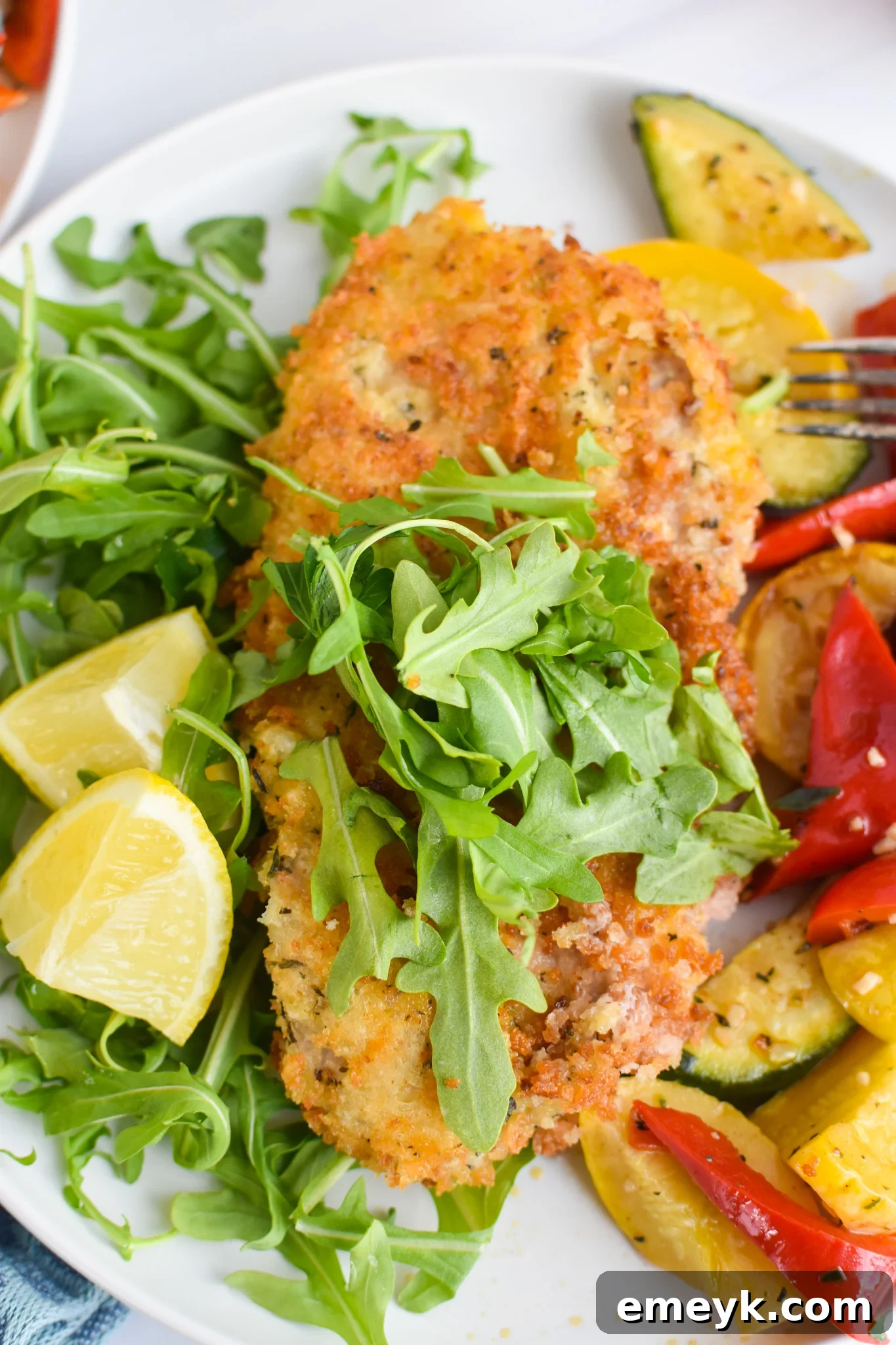 Perfectly crispy Veal Milanese served with a fresh arugula salad and lemon wedges, ready to eat.