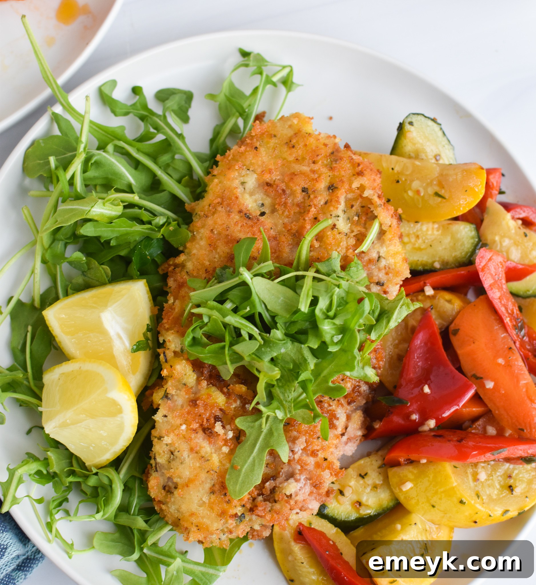 A close-up of a crispy Veal Milanese cutlet being lifted with a fork, showcasing its golden crust.