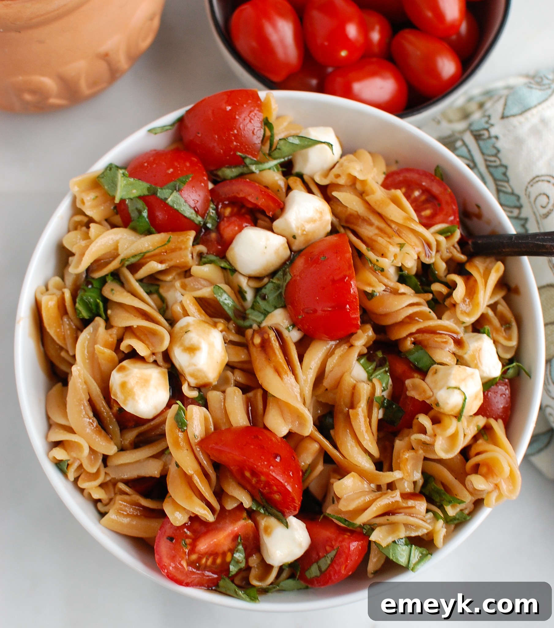 A serving of Caprese Pasta with a spoon, ready to eat