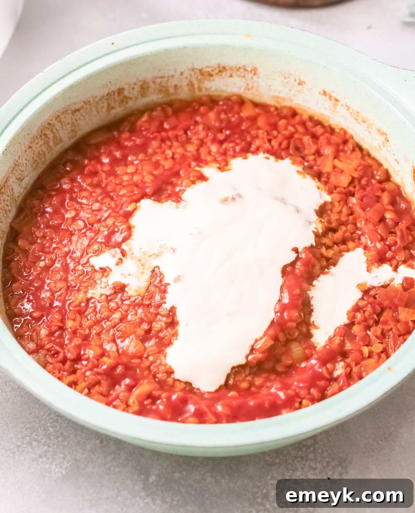 Red Lentil Curry being stirred with coconut cream.