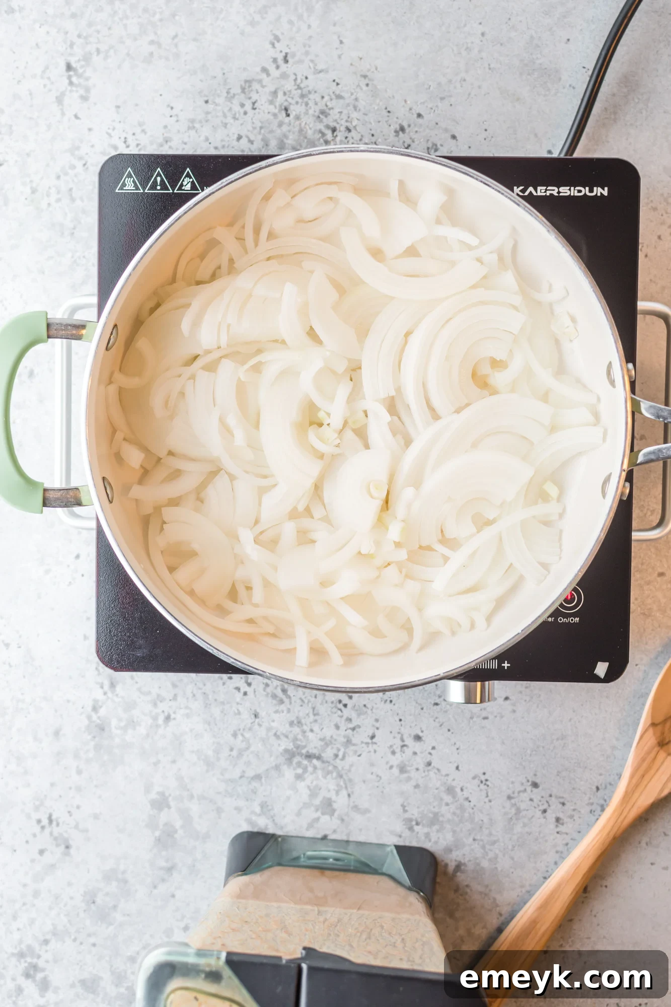Thinly sliced white onions sizzling in a skillet, turning translucent as they cook for the Chicken Tinga base.
