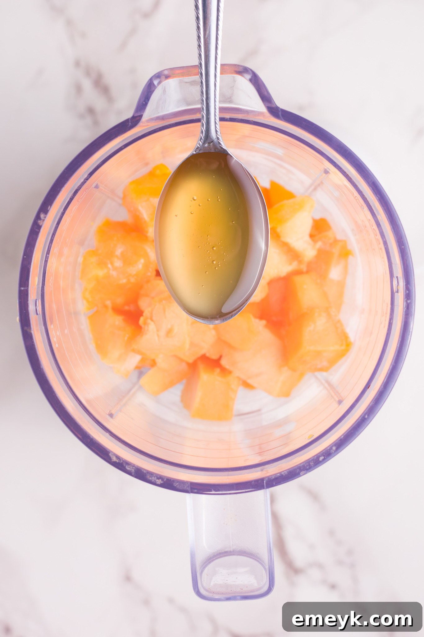 A blender filled with Mango Lassi ingredients, mid-blend, showing the smooth, creamy texture forming.