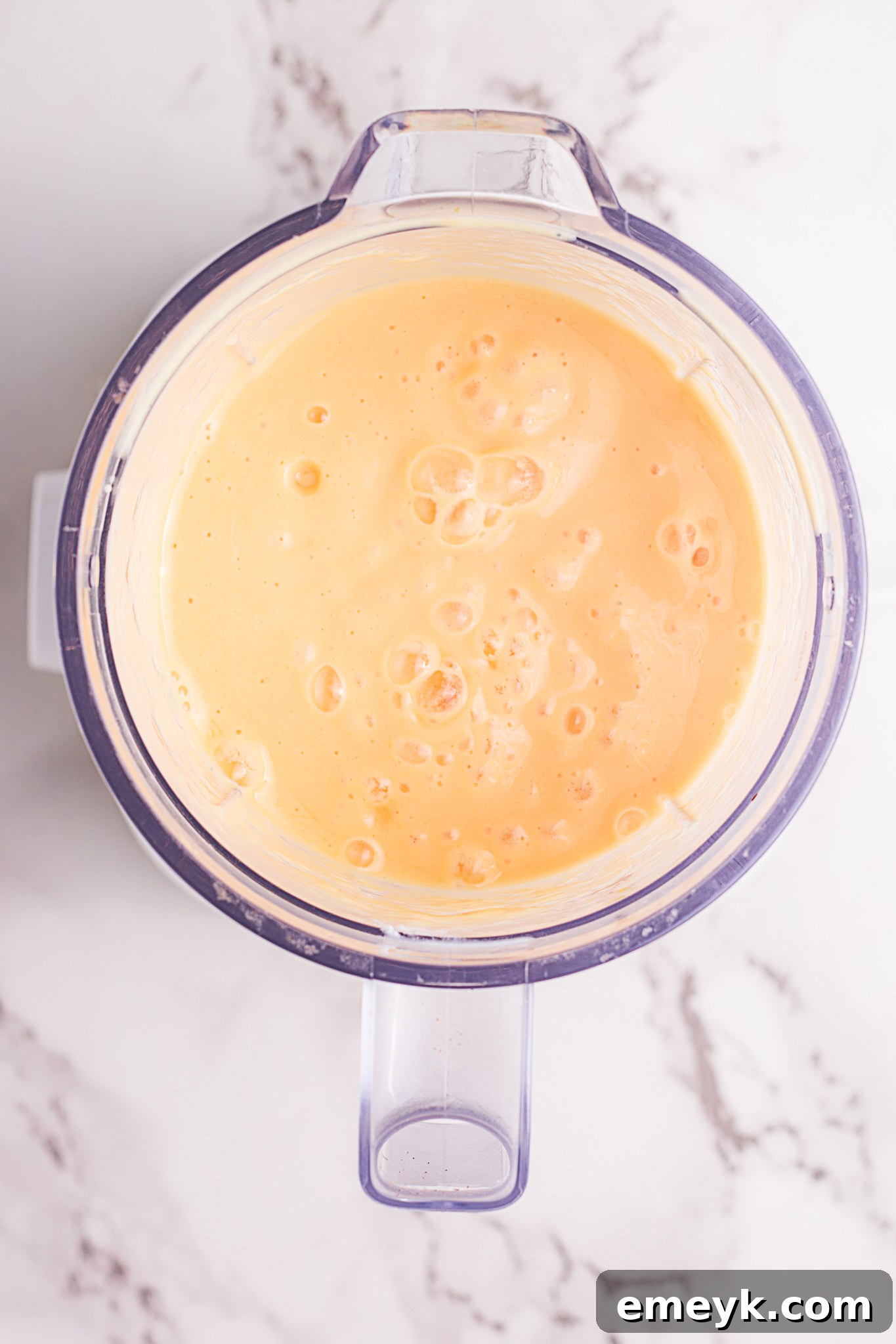 Close-up shot of a creamy Mango Lassi being poured from a blender into a glass.