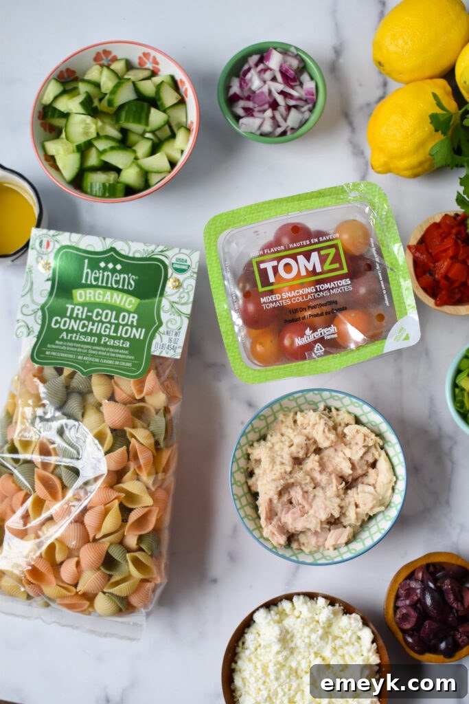 Individual ingredients for Mediterranean Tuna Pasta Salad laid out on a cutting board.