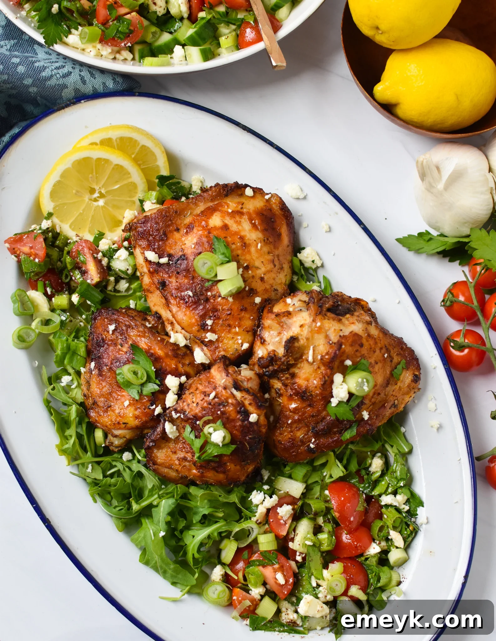 Air Fryer Mediterranean Chicken Thighs served on a white platter with a fresh salad.