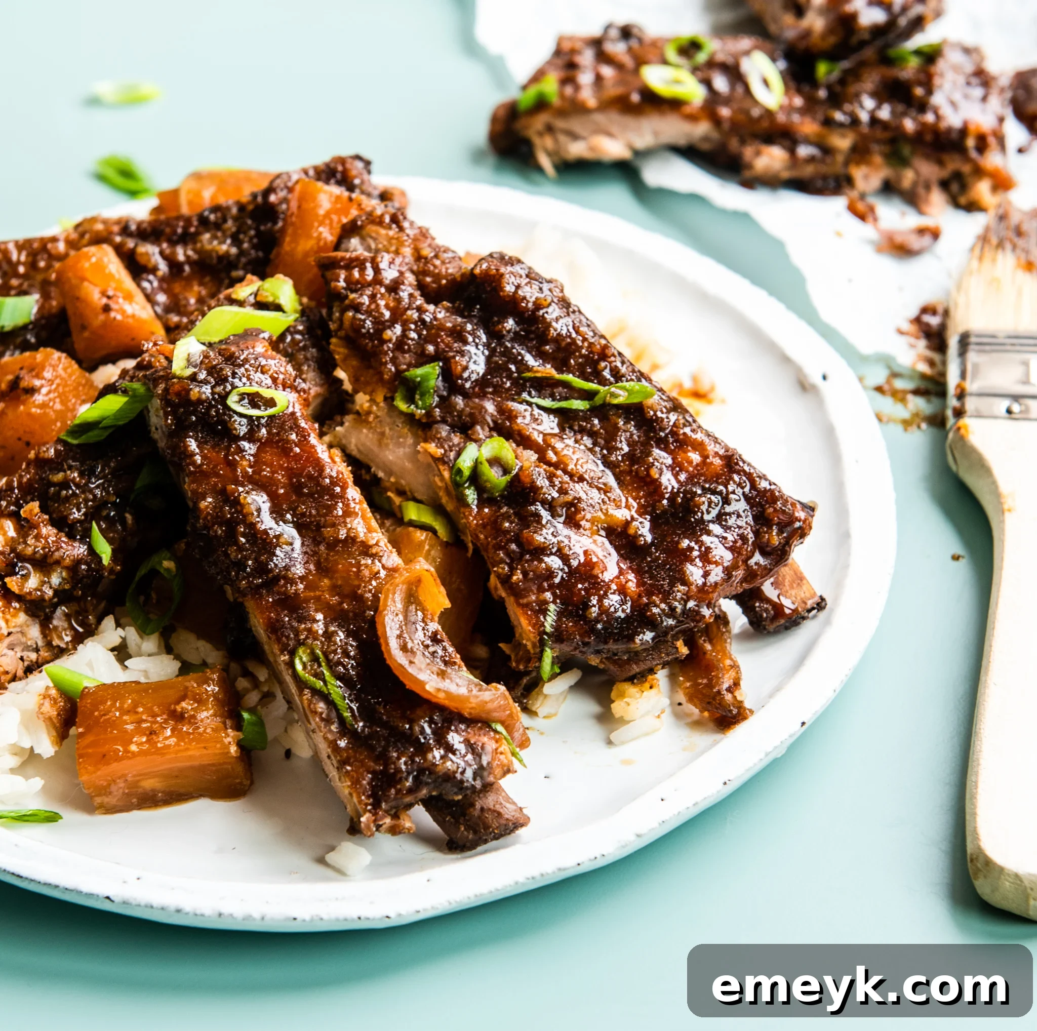 Plate of Slow Cooker Hawaiian Pork Ribs garnished with green onions and pineapple, ready to serve.