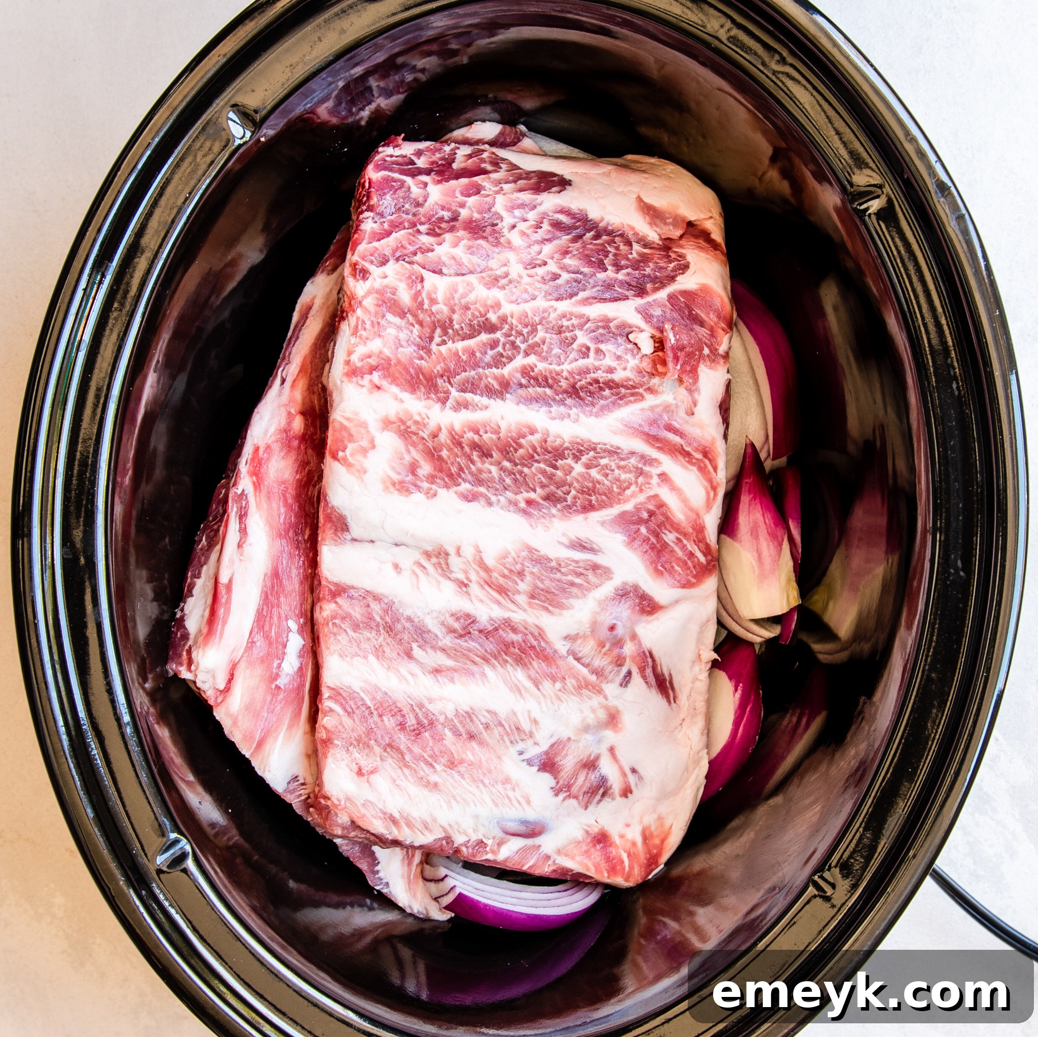 Slow Cooker filled with Hawaiian Pork Ribs simmering in sauce.