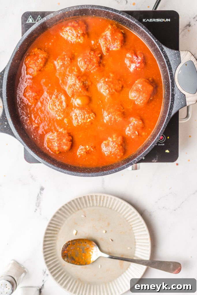 Albondigas en Chipotle meatballs simmering gently in the rich chipotle sauce in a pot.