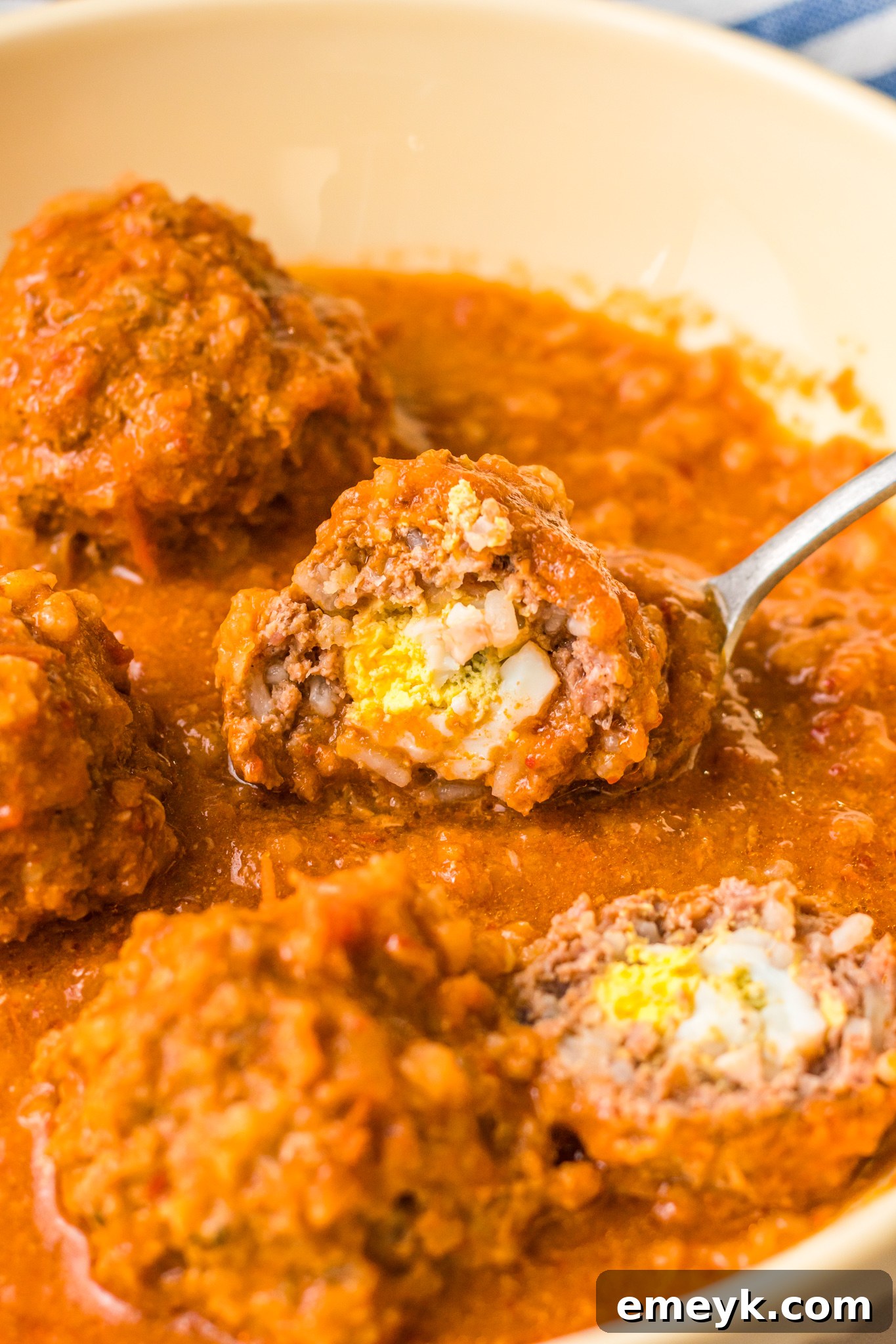 A cross-section of an Albondigas en Chipotle meatball, revealing the perfectly cooked boiled egg surprise inside.