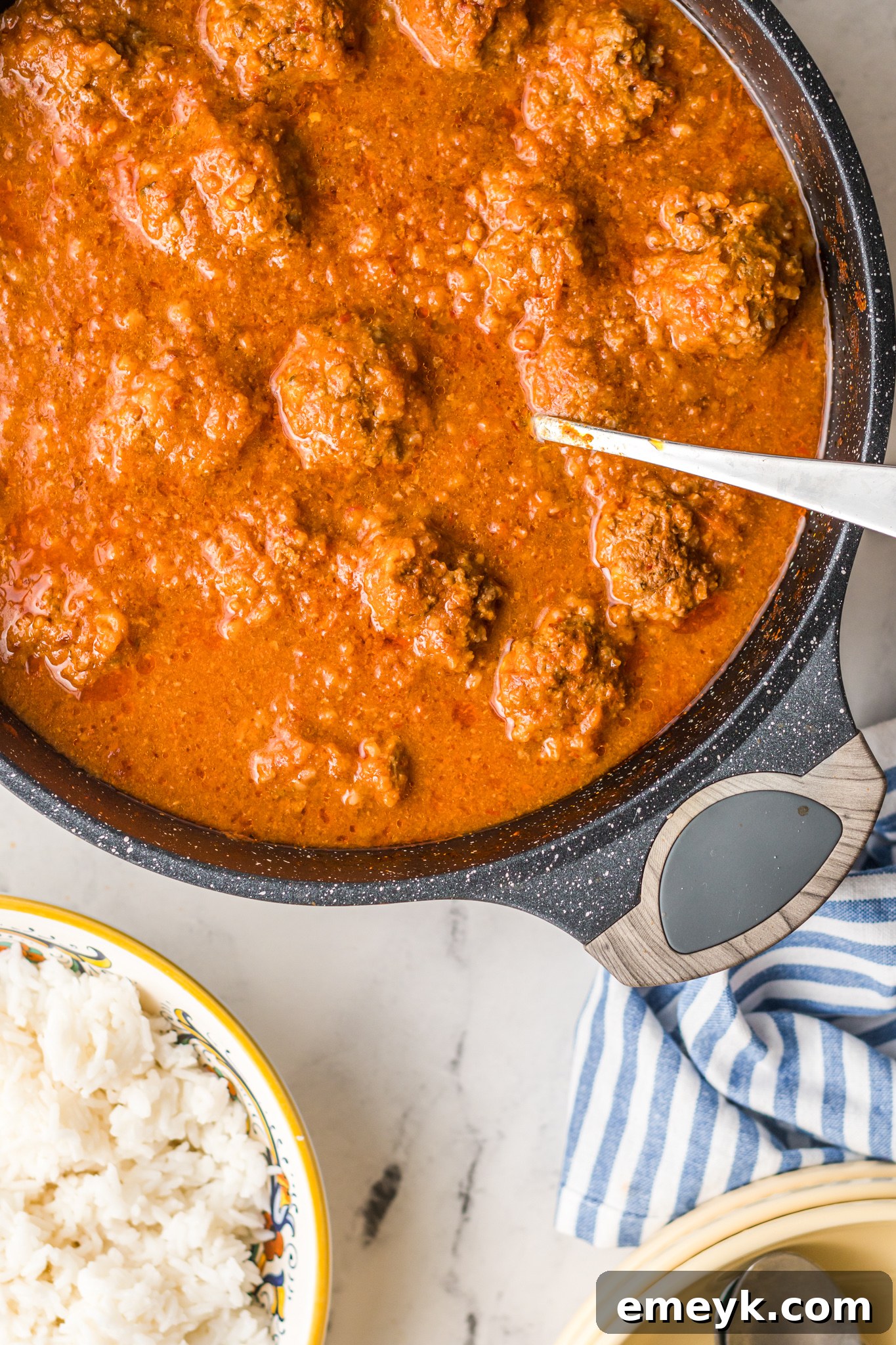 Close-up of Albondigas en Chipotle meatballs simmering in rich adobo sauce.