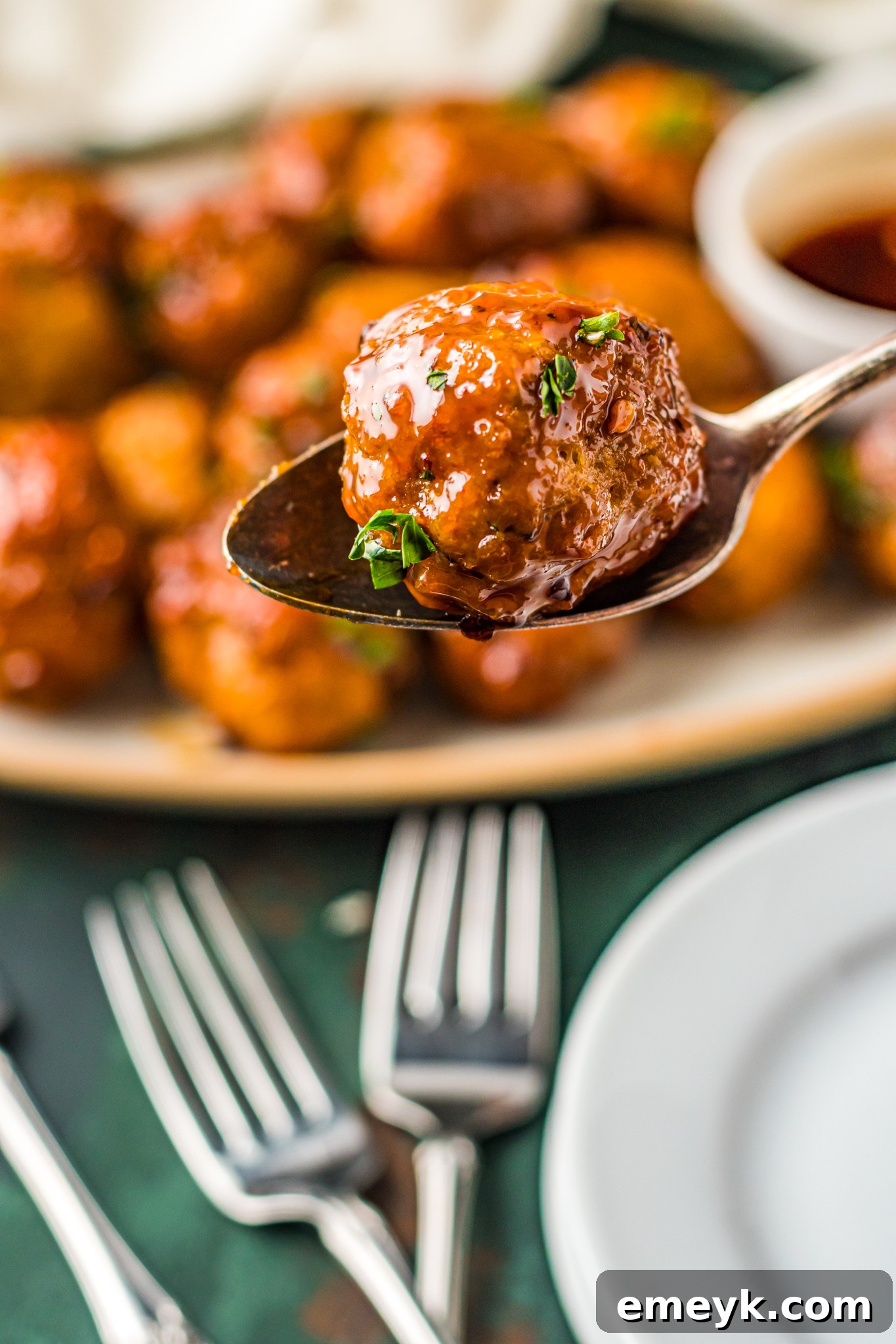 A single Air Fryer Meatball held delicately on a spoon, showcasing its perfect texture.
