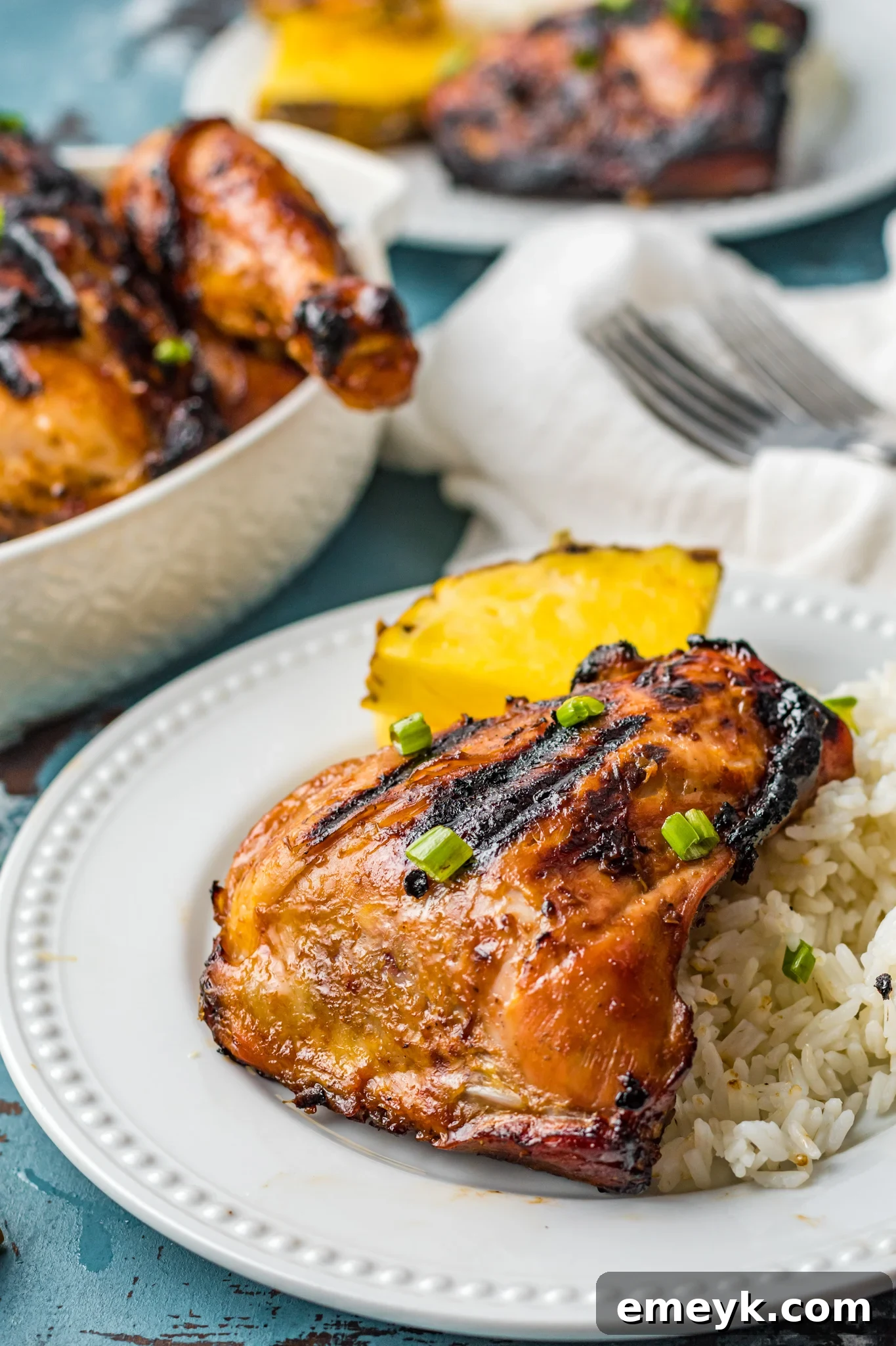 Golden Glazed Huli Huli Chicken 2 Perfectly grilled Huli Huli Chicken on a pristine white plate, garnished with fresh herbs and a slice of pineapple.