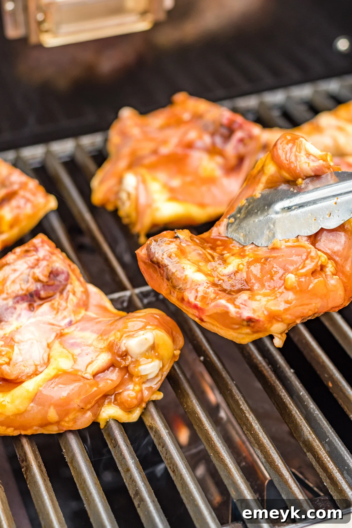 Golden Glazed Huli Huli Chicken 6 Huli Huli Chicken cooking on a barbecue grill, smoke rising, with visible grill marks.