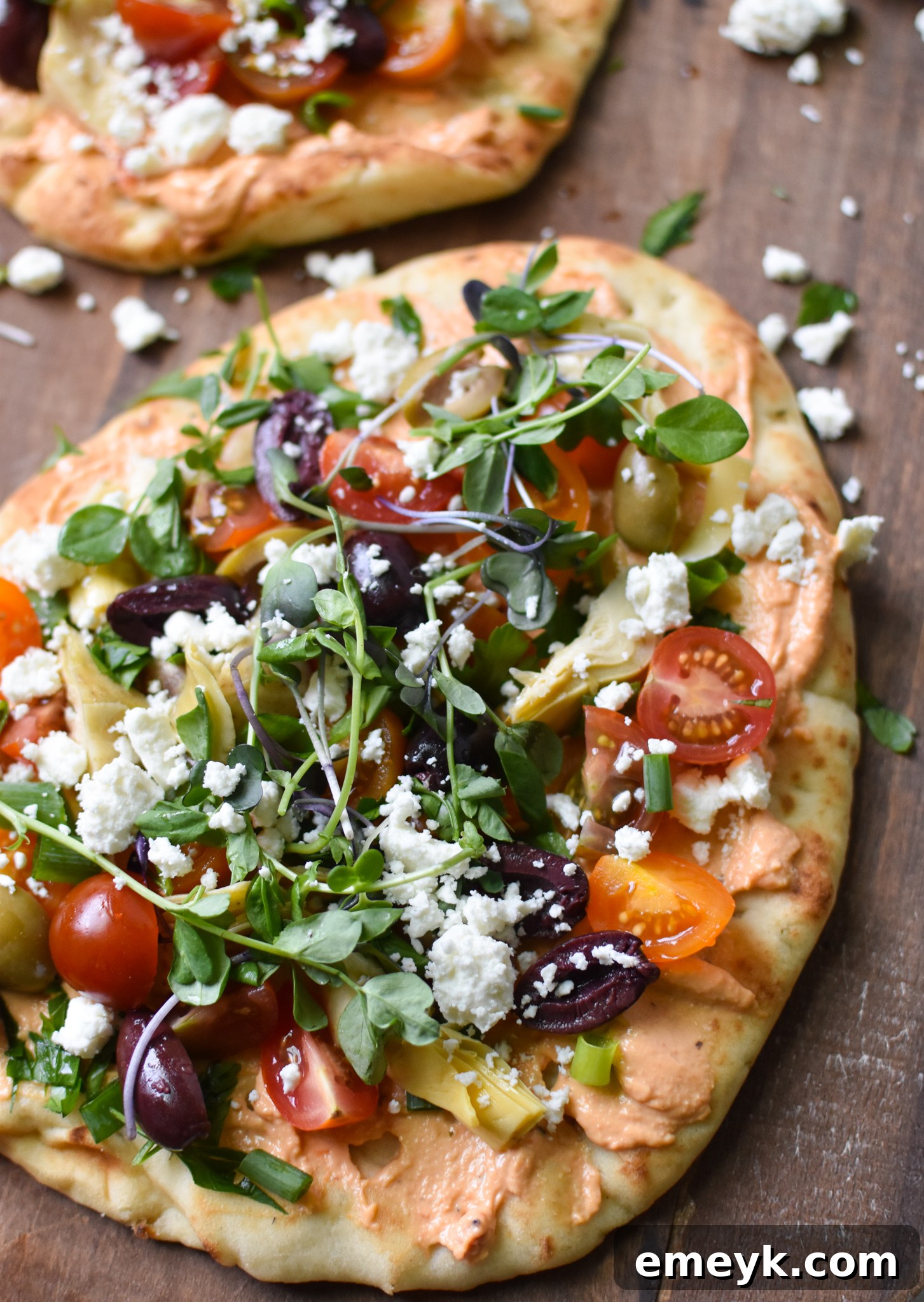 Mediterranean Naan Bread Pizza on a cutting board, garnished with fresh herbs.