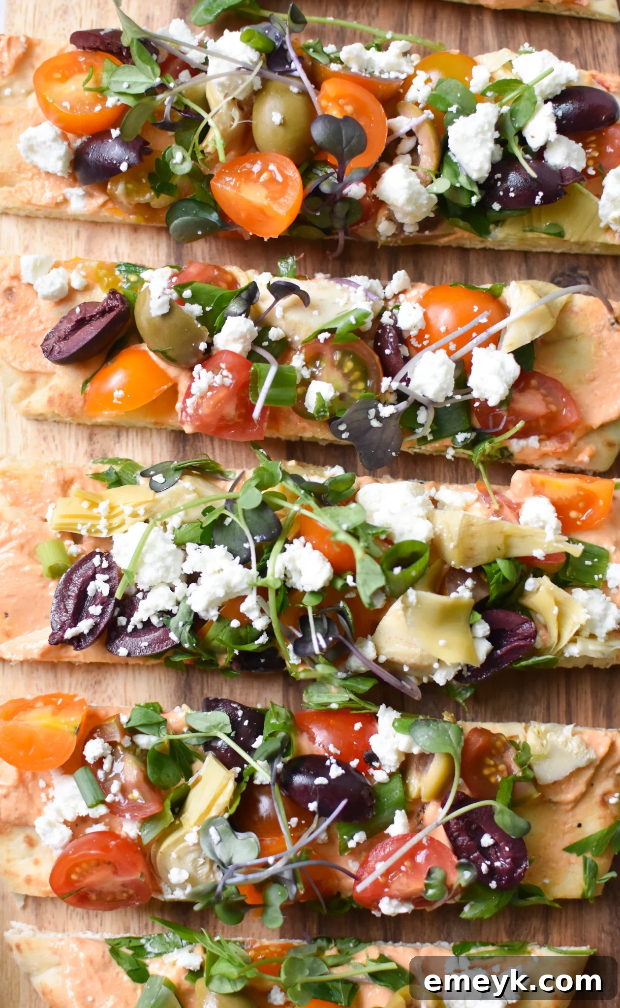 Mediterranean Naan Bread Pizza sliced into portions on a white plate.