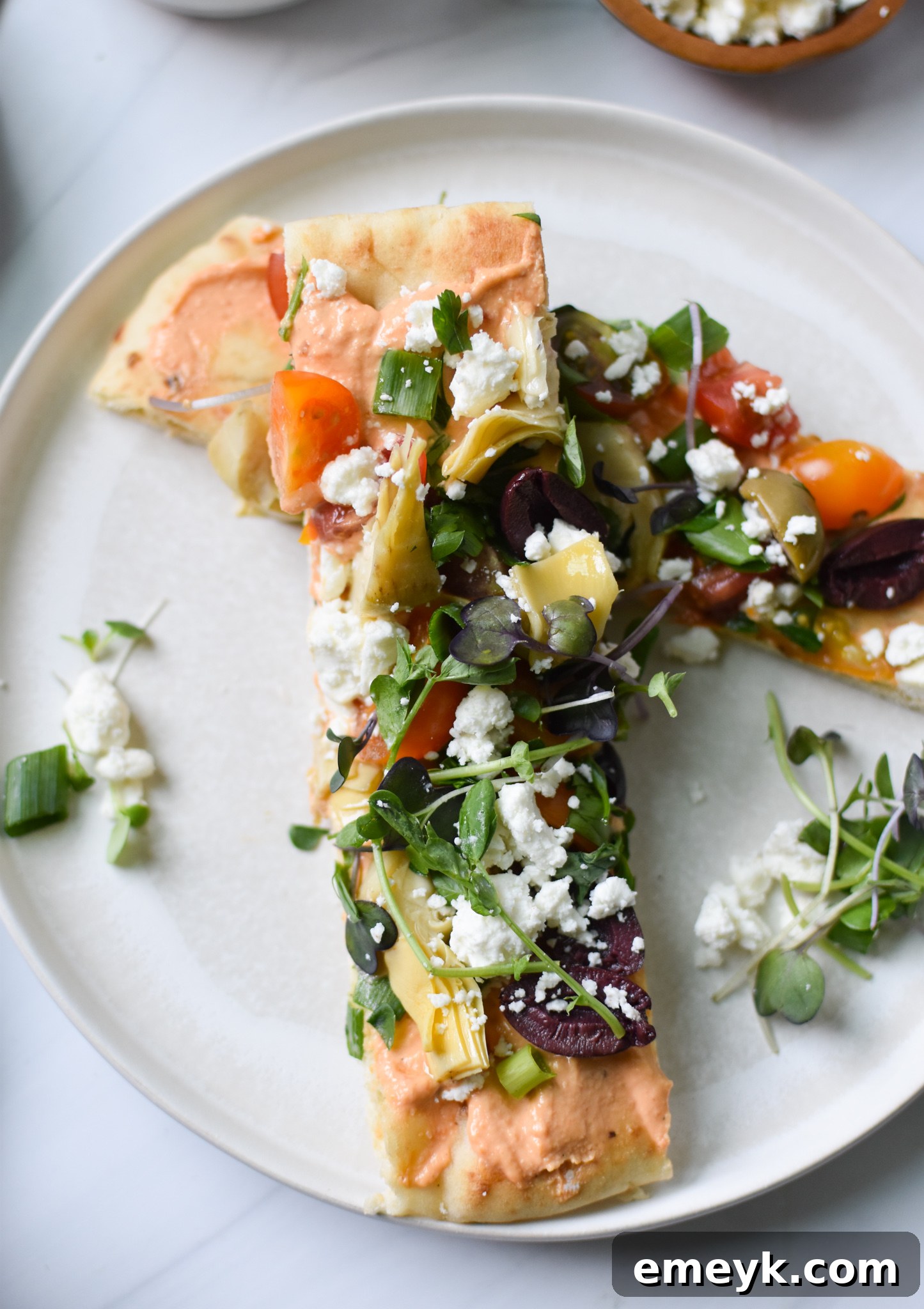 A whole Mediterranean Naan Bread Pizza on a decorative plate.