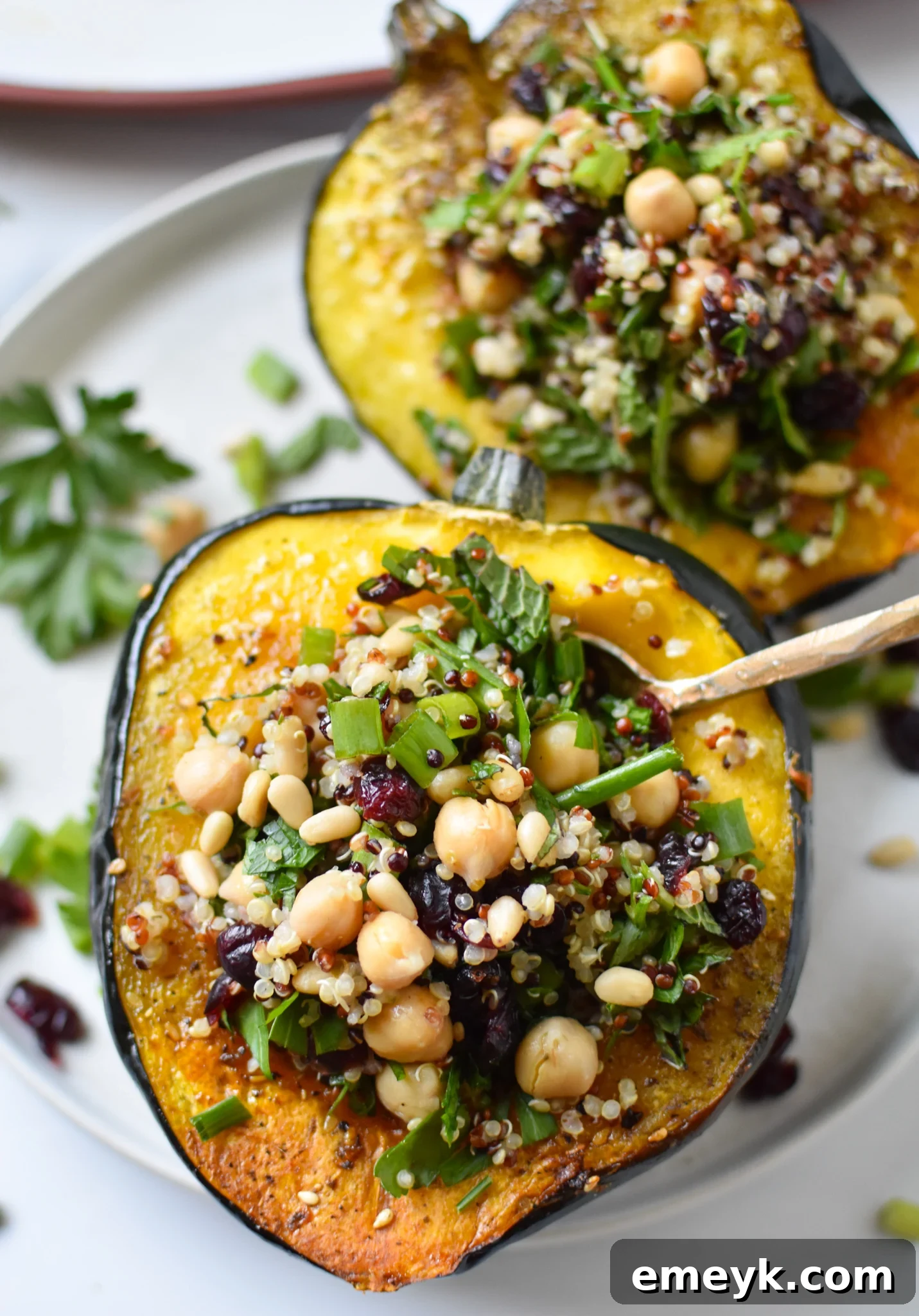Mediterranean Stuffed Acorn Squash being filled with quinoa mixture using a spoon.