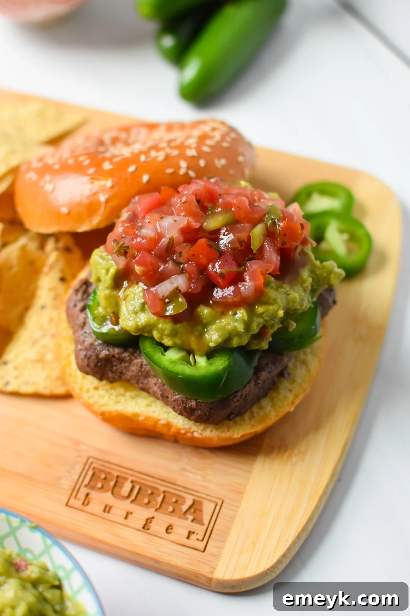Assembled Tex Mex Burger on a rustic wooden cutting board, ready to be sliced.