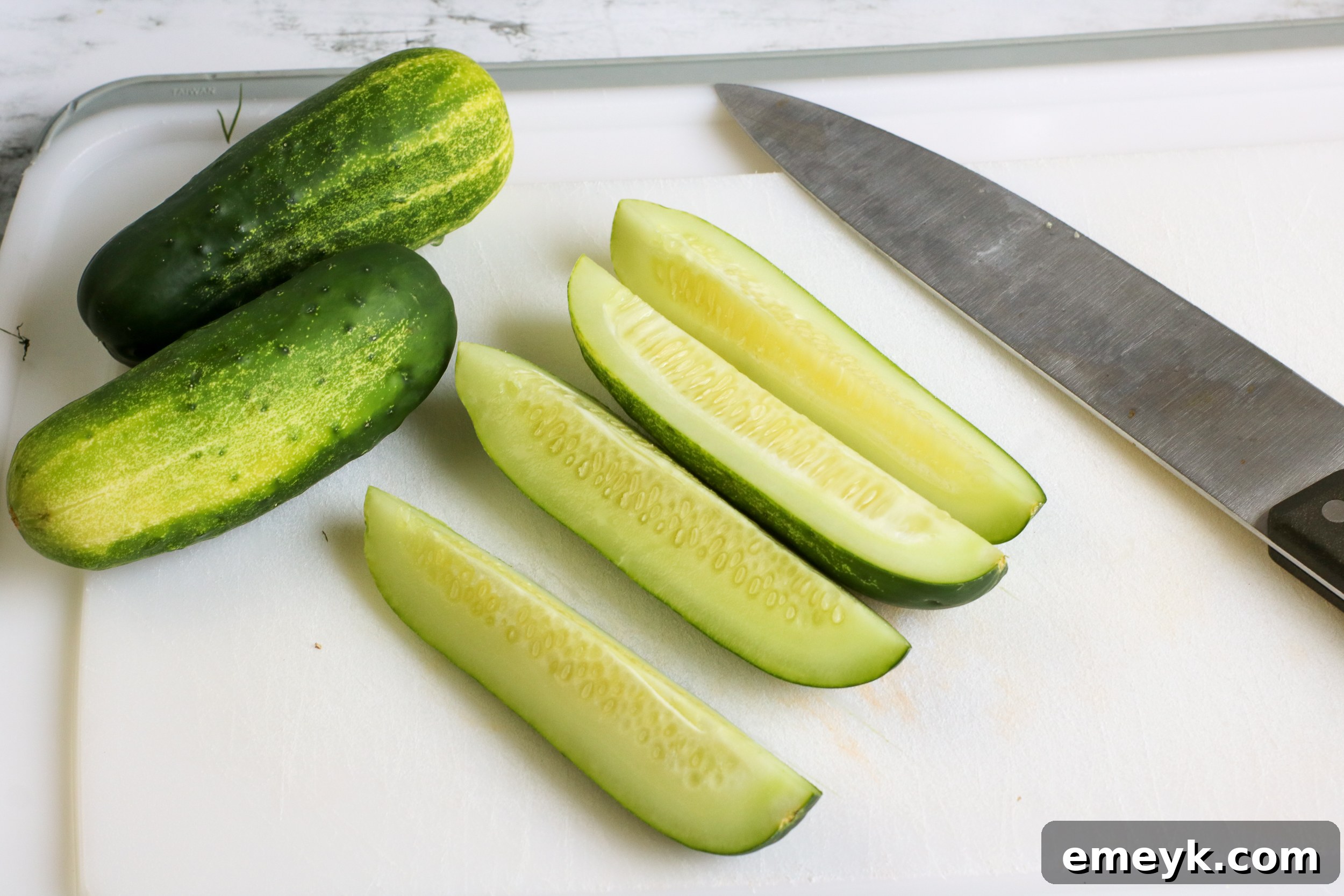 Close-up of fresh Refrigerator Dill Pickles on a cutting board, highlighting the dill and garlic.