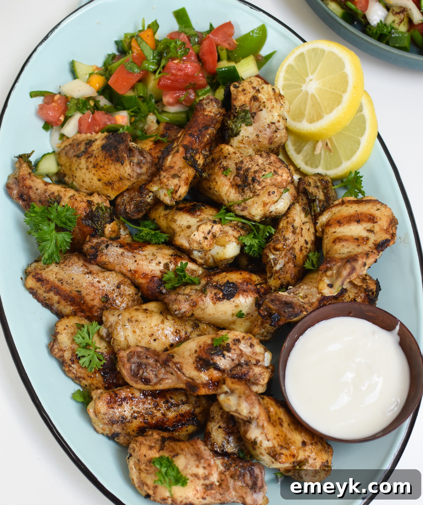 Grilled Mediterranean Chicken Wings on a blue platter, garnished with fresh herbs.