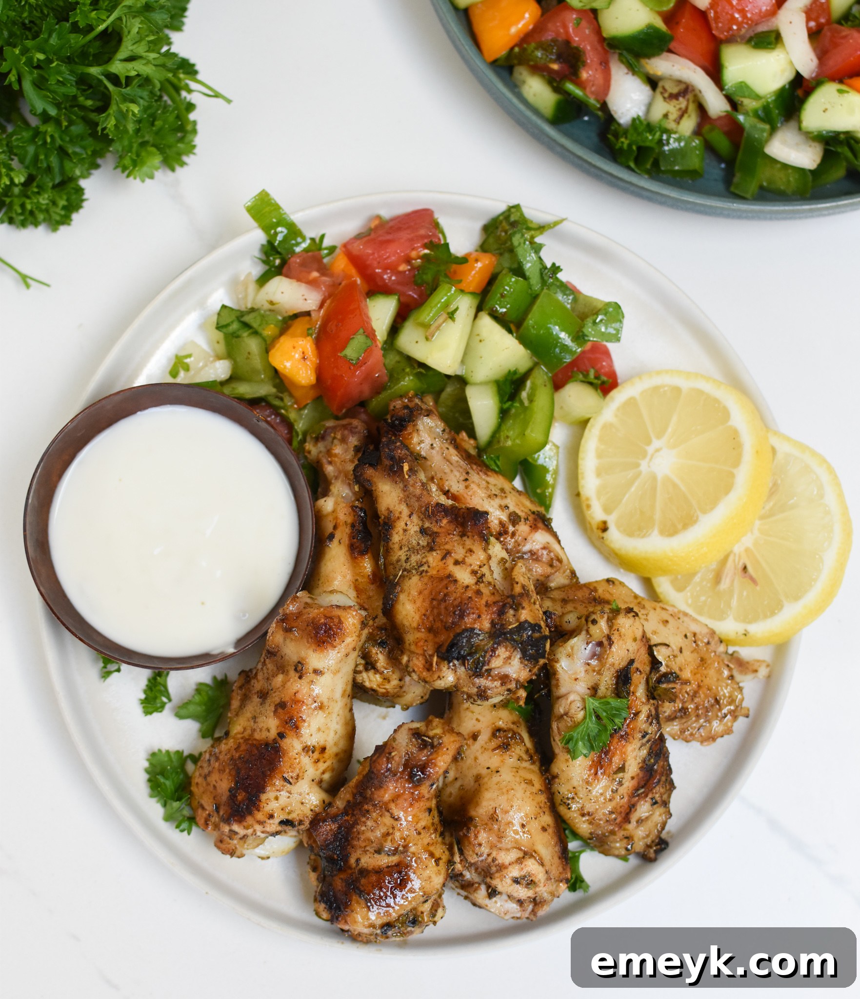 Grilled Mediterranean Chicken Wings garnished with fresh lemon wedges and herbs.