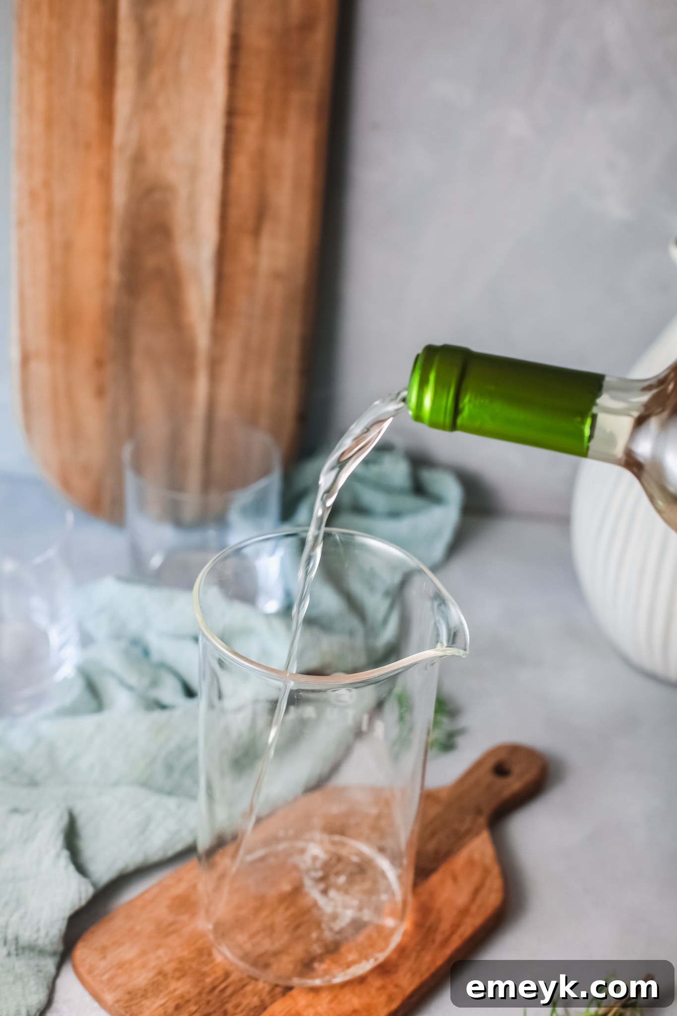 A hand pouring white wine into a glass for White Sangria.