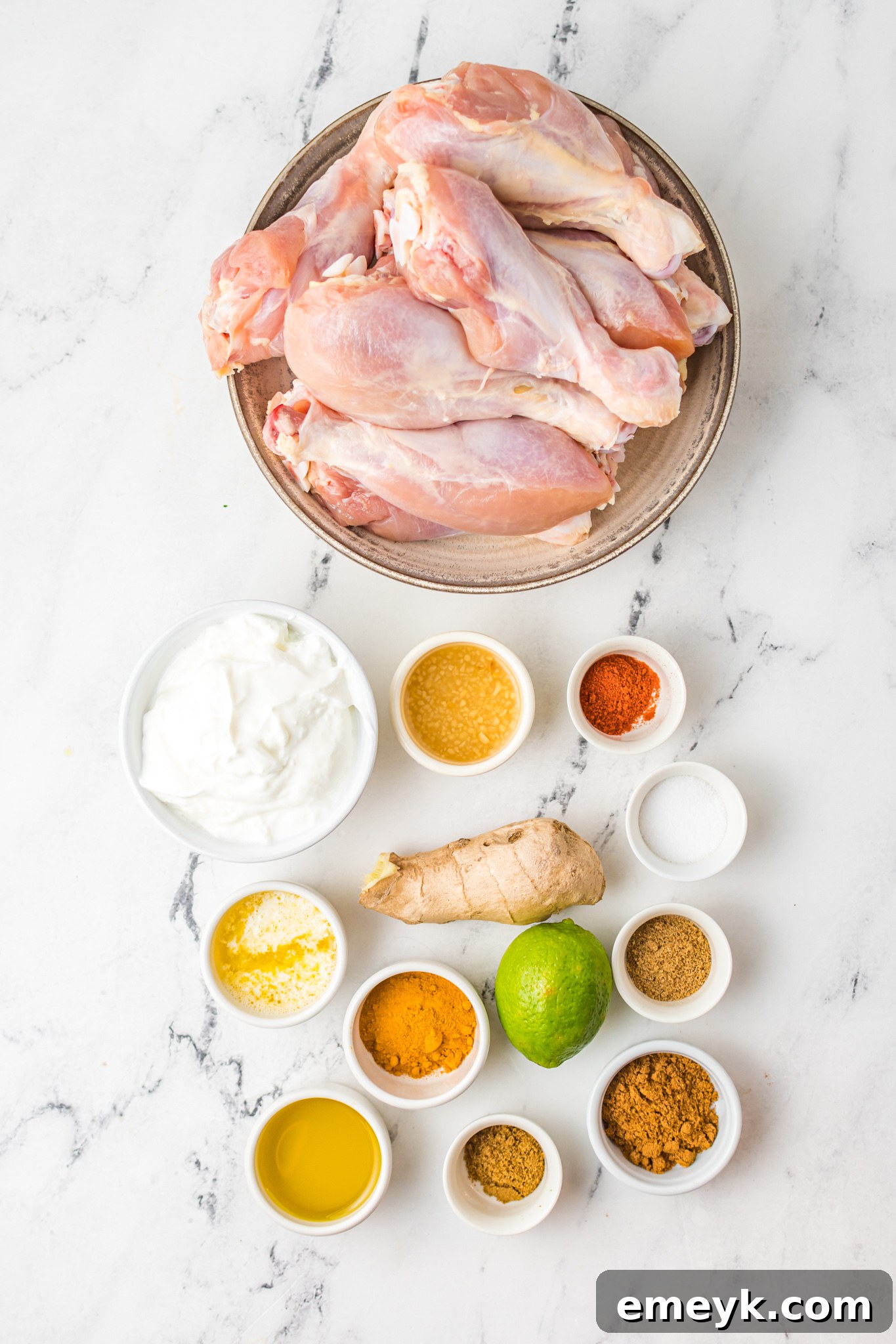 Crispy Air Fryer Tandoori Chicken Legs 3 A selection of fresh ingredients and spices laid out for making Air Fryer Tandoori Chicken Legs, including Greek yogurt, butter, lime, garlic, ginger, turmeric, garam masala, chili powder, cumin, and coriander.