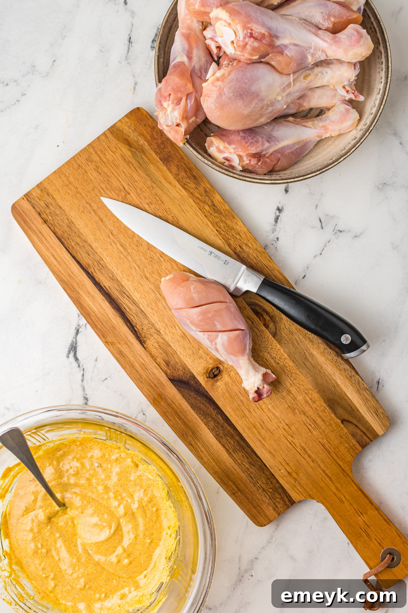 Crispy Air Fryer Tandoori Chicken Legs 5 Raw chicken legs with deep slices on a cutting board, prepared for marinating.