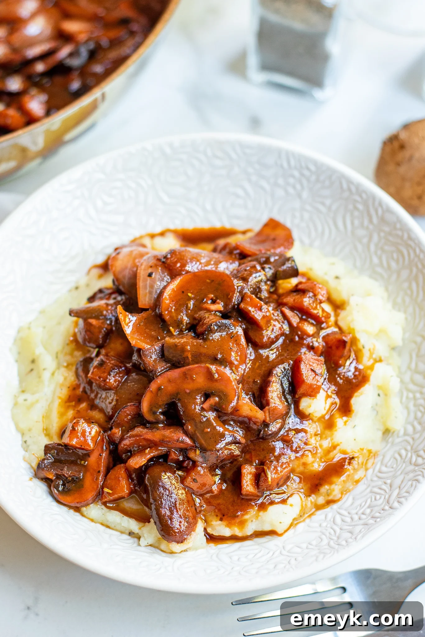 Mushroom Bourguignon on a white plate, garnished with fresh herbs.