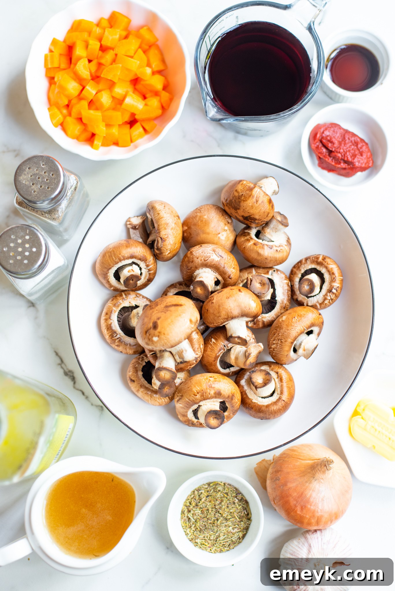 Fresh ingredients laid out for Mushroom Bourguignon: mushrooms, carrots, onions, herbs, wine, and broth.