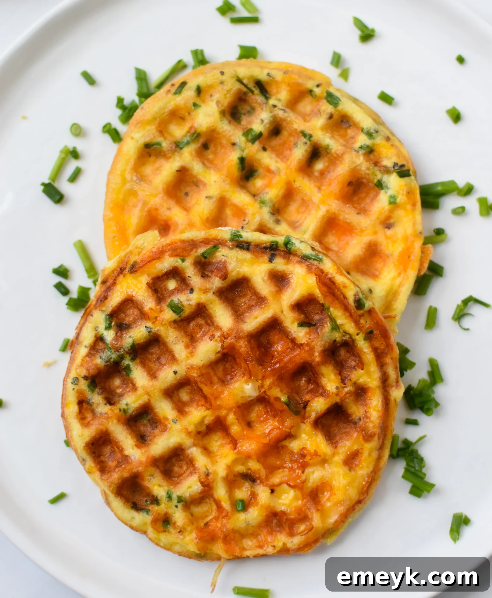 Crispy Keto Chaffles 70 Crispy golden chaffles served on a white plate, garnished with fresh chives, ready to be enjoyed as a low-carb breakfast.