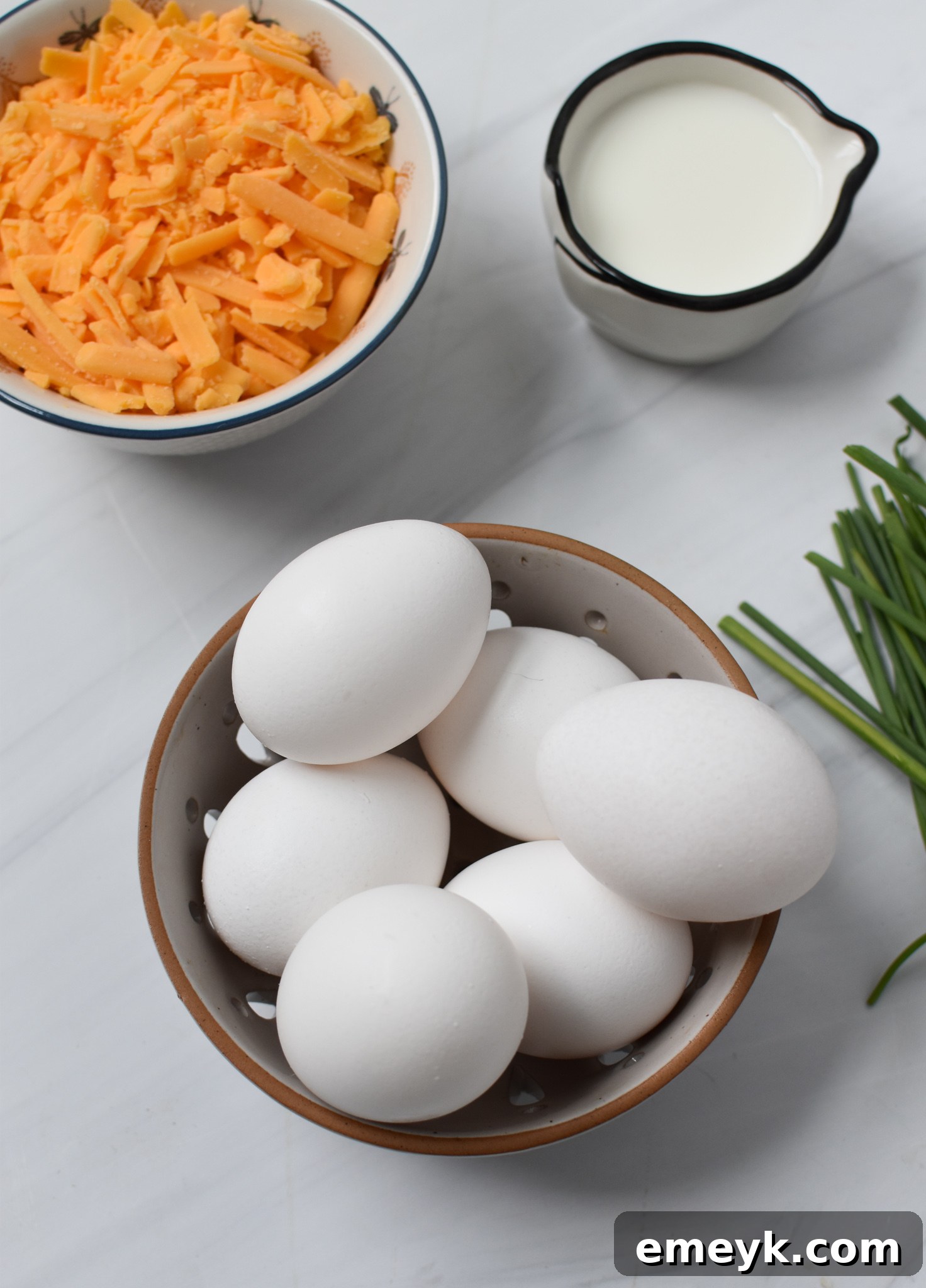 Fresh ingredients laid out for chaffles recipe, including eggs, shredded cheese, and chopped chives.