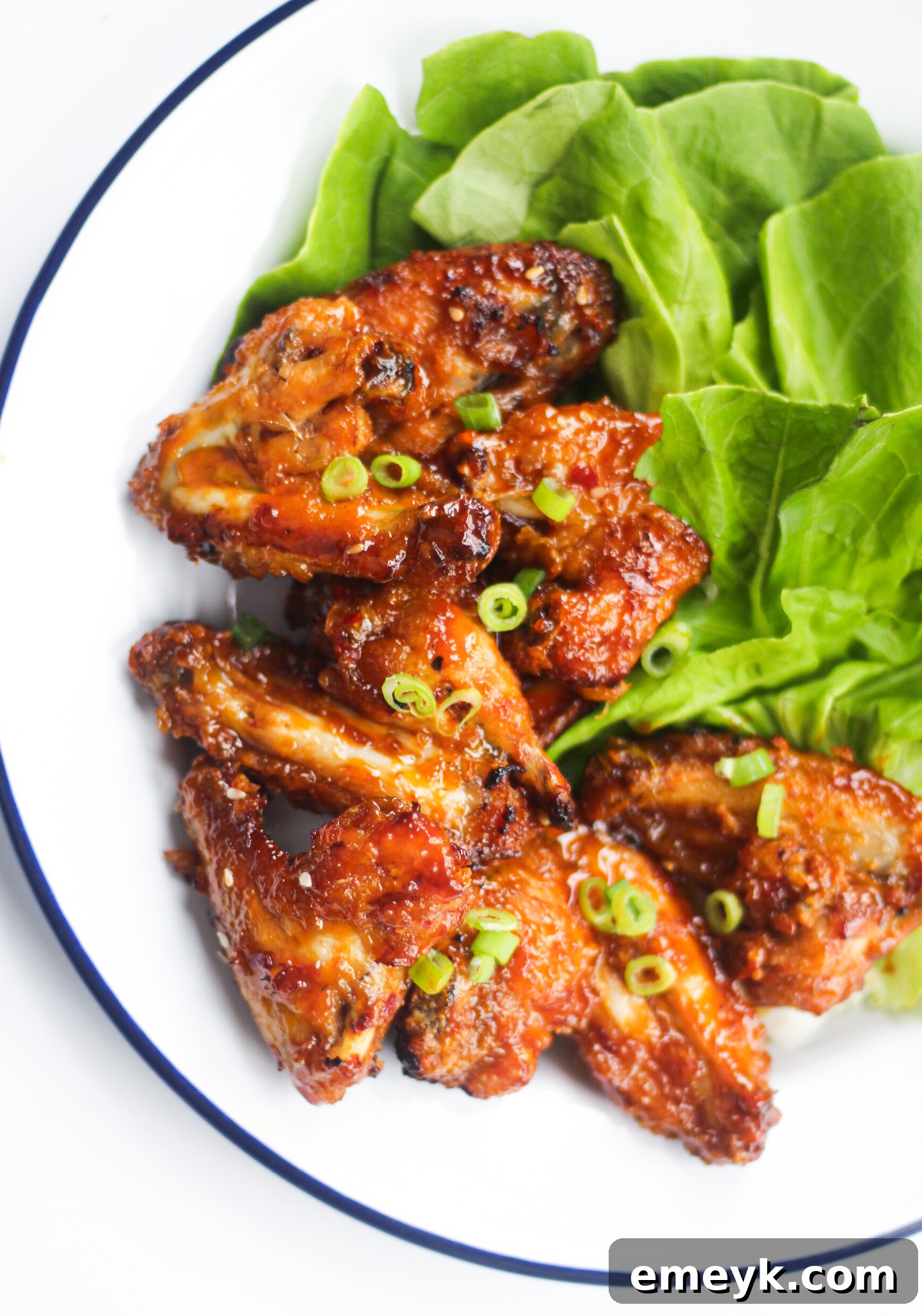 Air Fryer Chicken Wings Recipe on a white plate, garnished with green onions and sesame seeds.