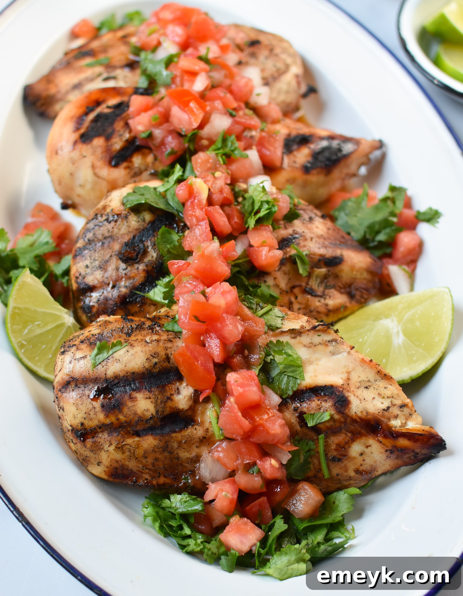 Tequila-Lime Grilled Chicken 4 Perfectly grilled Margarita Chicken, sliced and arranged on a platter with fresh lime wedges.