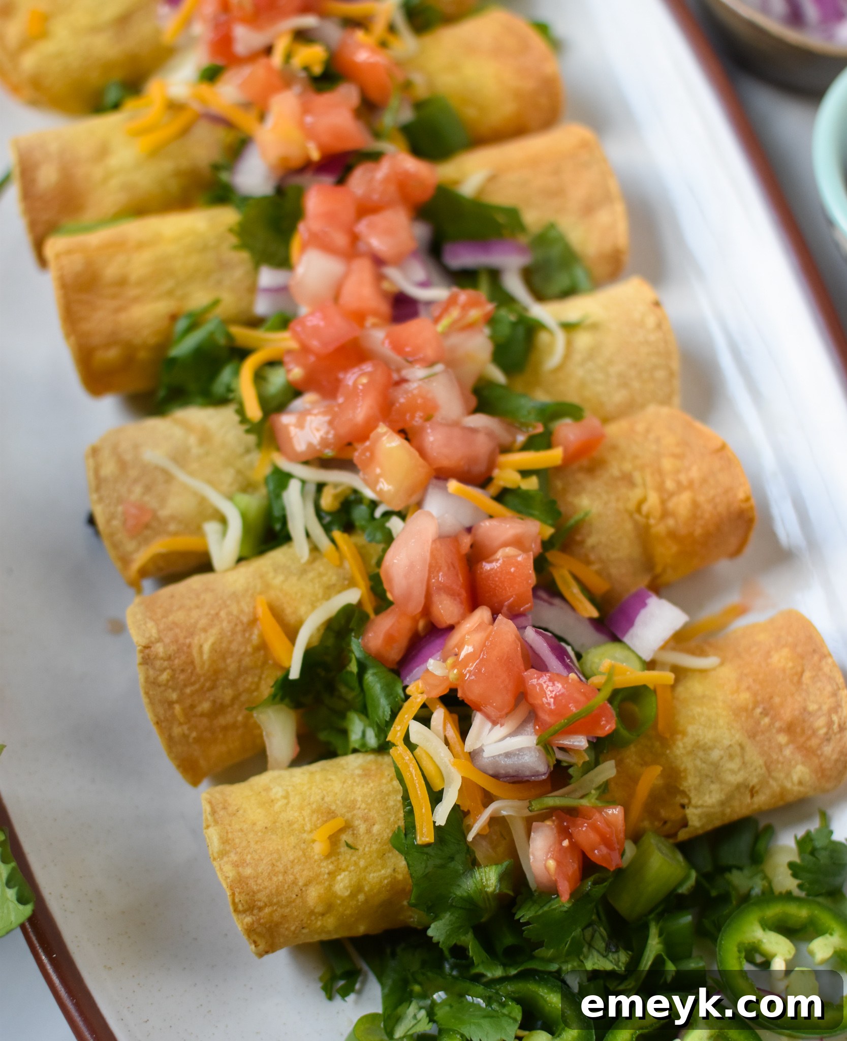 Close-up of golden brown Air Fryer Pork Taquitos generously garnished with fresh cilantro.